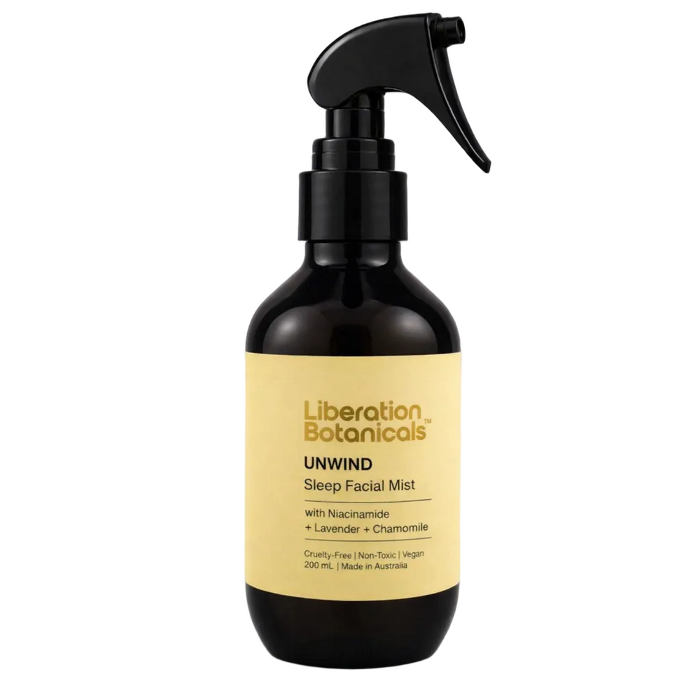 A 200 mL dark amber glass spray bottle of Liberation Botanicals Unwind Sleep Facial Mist with a black trigger sprayer and a pale yellow label, set against a neutral gray background.