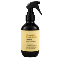 A 200 mL dark amber glass spray bottle of Liberation Botanicals Unwind Sleep Facial Mist with a black trigger sprayer and a pale yellow label, set against a neutral gray background.