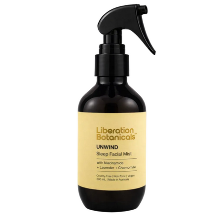 A 200 mL dark amber glass spray bottle of Liberation Botanicals Unwind Sleep Facial Mist with a black trigger sprayer and a pale yellow label, set against a neutral gray background.
