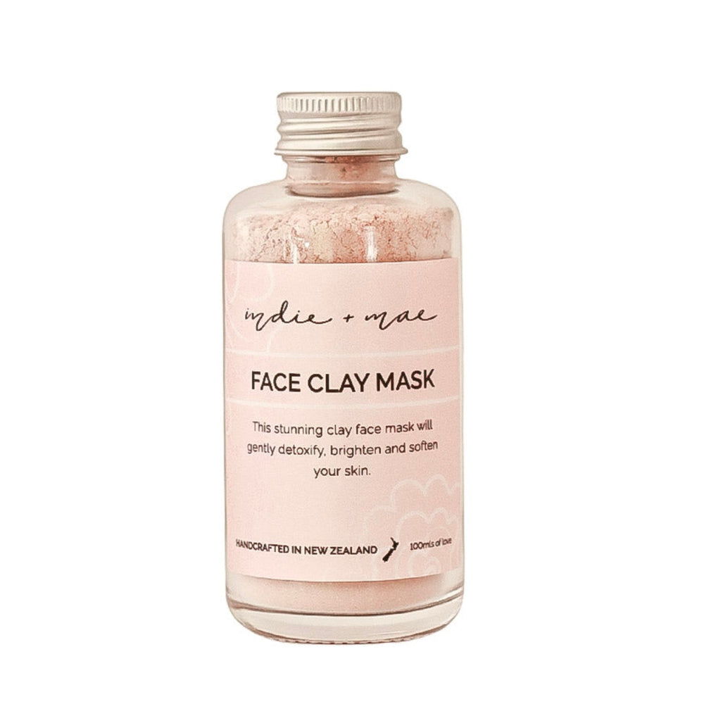 A clear glass bottle of 'indie or not' Face Clay Mask with a light pink label and a silver metal cap, containing a light pink clay powder, shown on a plain white background.