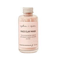 A clear glass bottle of 'indie or not' Face Clay Mask with a light pink label and a silver metal cap, containing a light pink clay powder, shown on a plain white background.